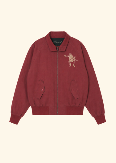 A burgundy zip-up jacket with a small beige embroidered lion graphic on the left chest, displayed flat against a light cream background.