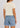 A woman shown from the back wearing a light cream short-sleeve crop top and light blue denim shorts with a frayed hem.