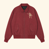 A burgundy zip-up jacket with a small beige embroidered lion graphic on the left chest, displayed flat against a light cream background.