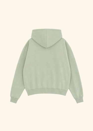 A sage green pullover hoodie shown from the back, featuring a relaxed fit, ribbed cuffs, and a ribbed hem, displayed against a solid cream background.