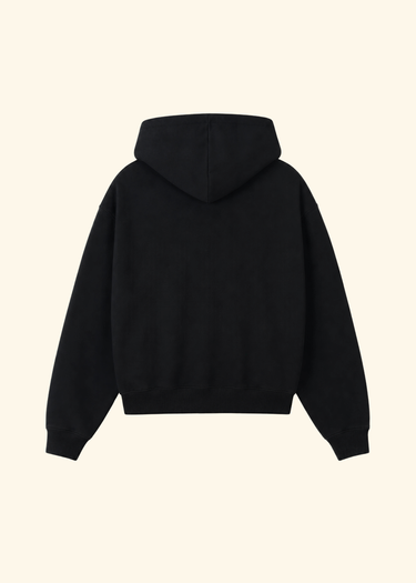 A black pullover hoodie shown from the back, photographed flat against a solid, warm off-white background.
