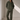 A woman stands in a minimalist studio wearing an olive green corduroy button-up jacket and matching wide-leg corduroy pants.