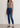 Woman wearing a gray tank top and Noend blue jeans against a plain background