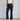 Woman wearing dark blue cropped flare jeans and white sneakers on a plain background