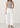 Person wearing a gray tank top and Noend white pants on a plain background