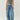 Person wearing a gray tank top and blue jeans on a plain background