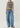 Person wearing a gray tank top and blue jeans on a plain background