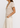 Woman wearing a beige V-neck top and pants on a white background