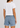 A model shown from the back wearing a white short-sleeve crop top and light blue denim shorts with a frayed hem.