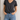 Person wearing a Noend grey V-neck t-shirt and blue jeans against a neutral background