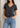 Person wearing a Noend grey V-neck t-shirt and blue jeans against a neutral background