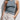 Person wearing a gray tank top and light-colored pants against a white background