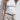 Person wearing a white tank top and beige pants against a white background