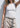 Person wearing a white tank top and beige pants against a white background