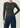 Person wearing a Noend dark green ribbed top and blue jeans on a light gray background